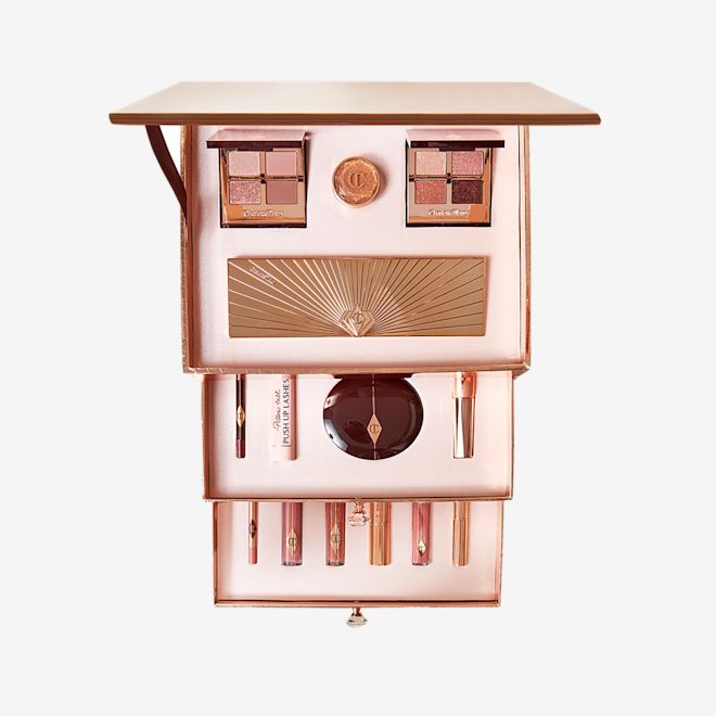 PIllow Talk Dreams Come True Box open An open makeup kit with two quad eyeshadow palettes, cream eyeshadow in a pot, and a large 12-pan eyeshadow palette, blush compact, mascara, eyeliner pencil, highlighter wand, nude pink lip liner pencil, nude pink lipstick, lipstick lip balm, and three lip glosses.