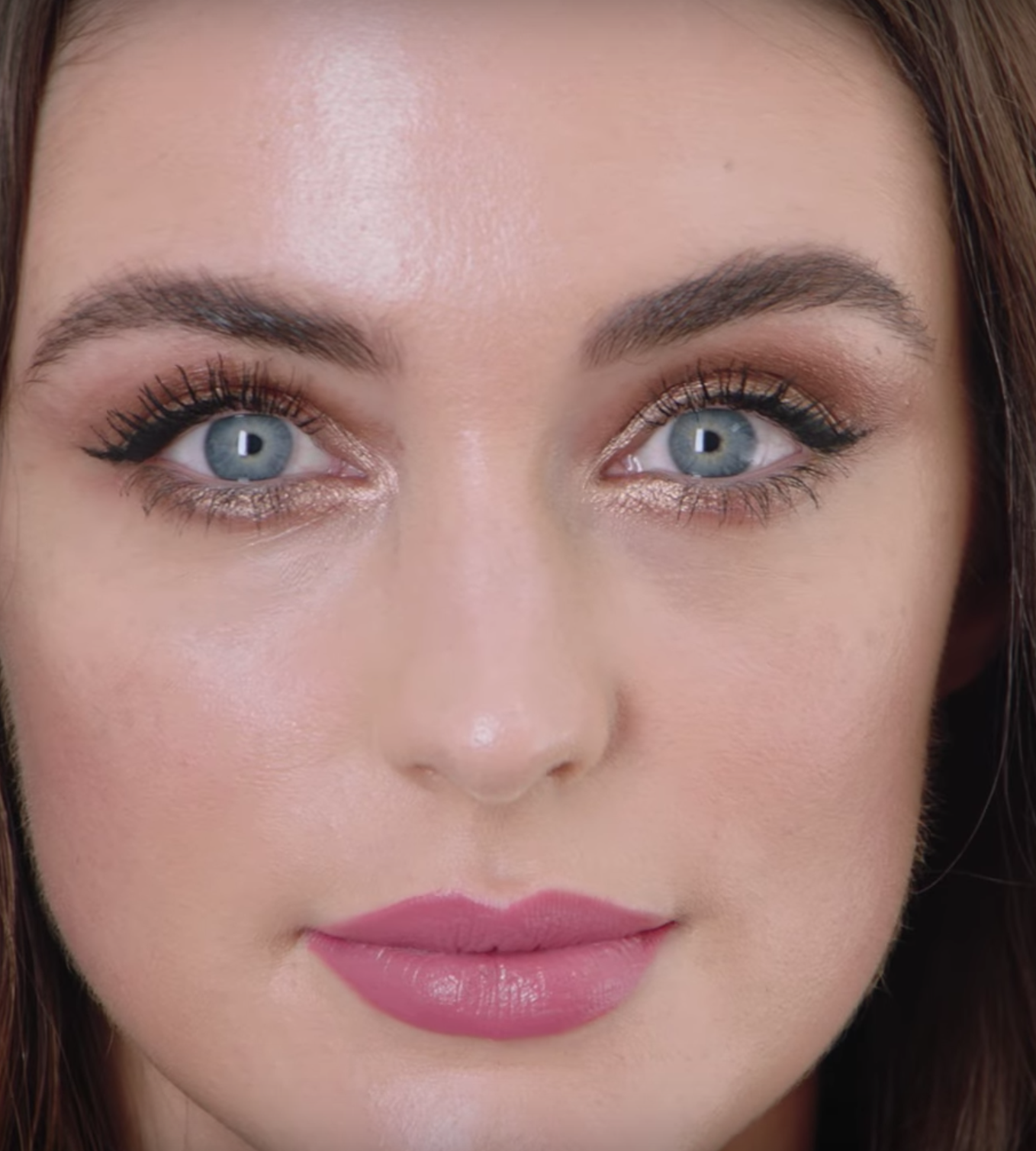 A fair-tone model with blue eyes wearing shimmery cream and champagne eye makeup that makes her eyes look brighter with a matte lipstick in a magenta shade.