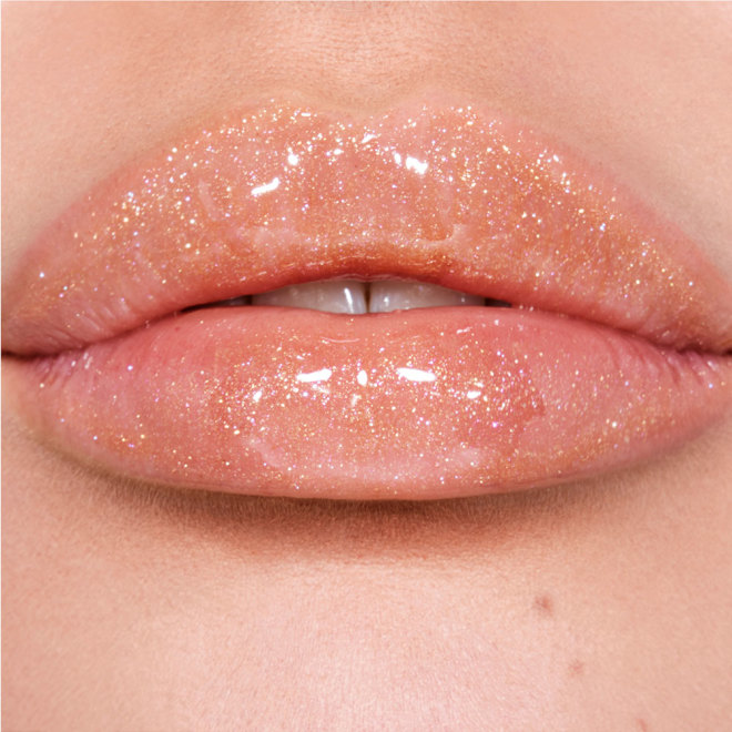 Lips close-up of a fair-tone model wearing a shimmery lip gloss in a rosy champagne shade with fine glitter.
