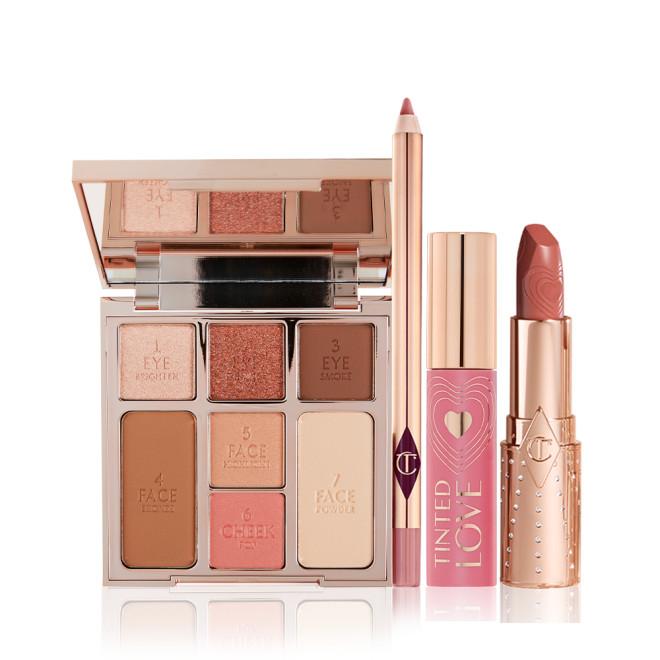 An open face palette with three eyeshadows, two blushes, and contour powders, lip liner pencil in nude pink, lip and cheek tint in a soft pink tube with a gold-coloured lid, and open lipstick in a nude pink shade with a gold-coloured tube. 