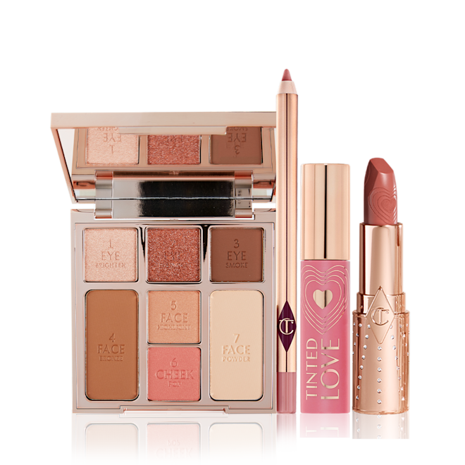The Look of Love Kit open An open face palette with three eyeshadows, two blushes, and contour powders, lip liner pencil in nude pink, lip and cheek tint in a soft pink tube with a gold-coloured lid, and open lipstick in a nude pink shade with a gold-coloured tube.