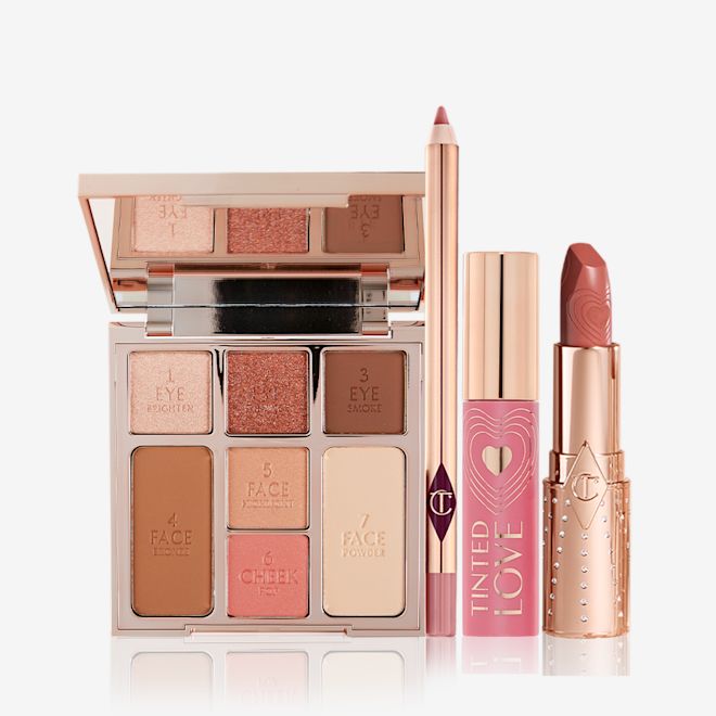 The Look of Love Kit open An open face palette with three eyeshadows, two blushes, and contour powders, lip liner pencil in nude pink, lip and cheek tint in a soft pink tube with a gold-coloured lid, and open lipstick in a nude pink shade with a gold-coloured tube.