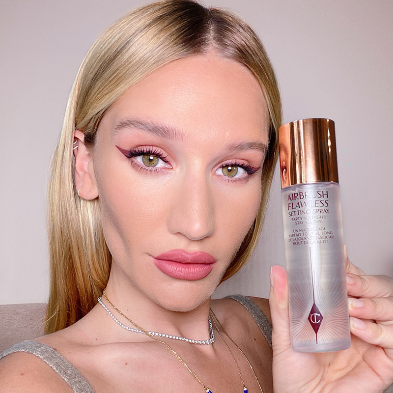 Sofia Tilbury holding a setting spray in a clear bottle with a gold-coloured lid.