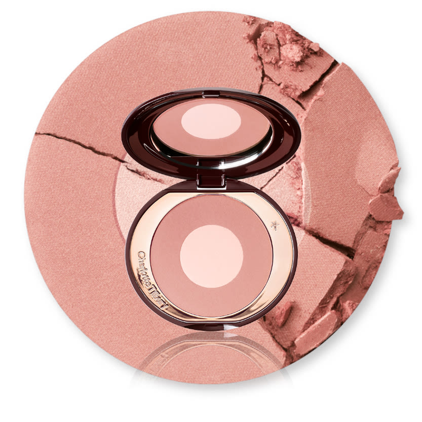 Cheek to Chic in Pillow Talk open with swatch An open, mirrored-lid two, tone powder blush in rose gold and champagne with its swatch behind it.