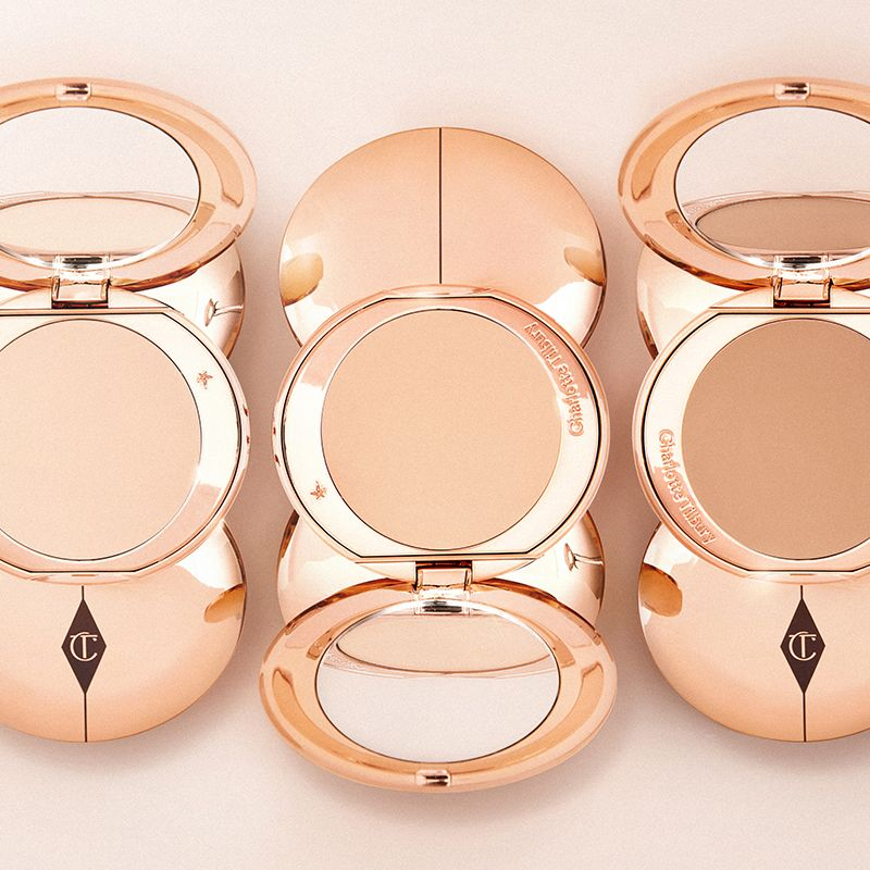Open, pressed powder compacts in different shades with mirrored lids in rose-gold packaging. 