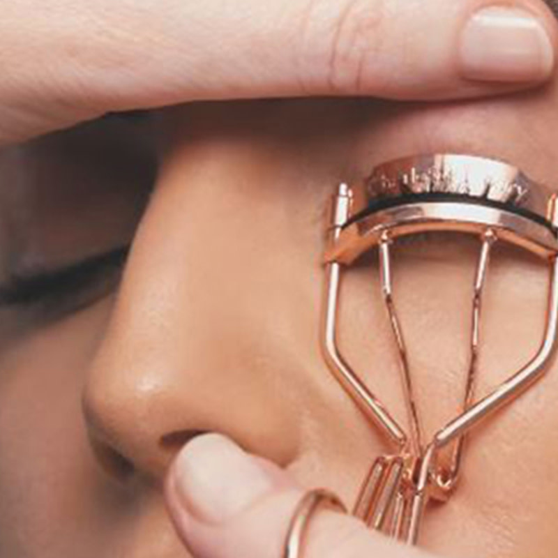 A medium-tone model displaying how to use eyelash curlers