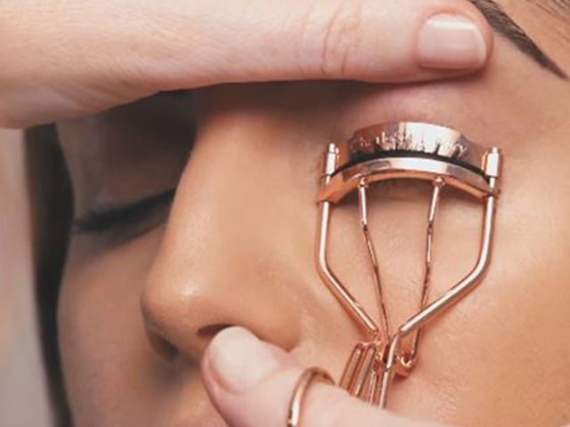 Model using an eyelash curler A medium-tone model using an eyelash curler.