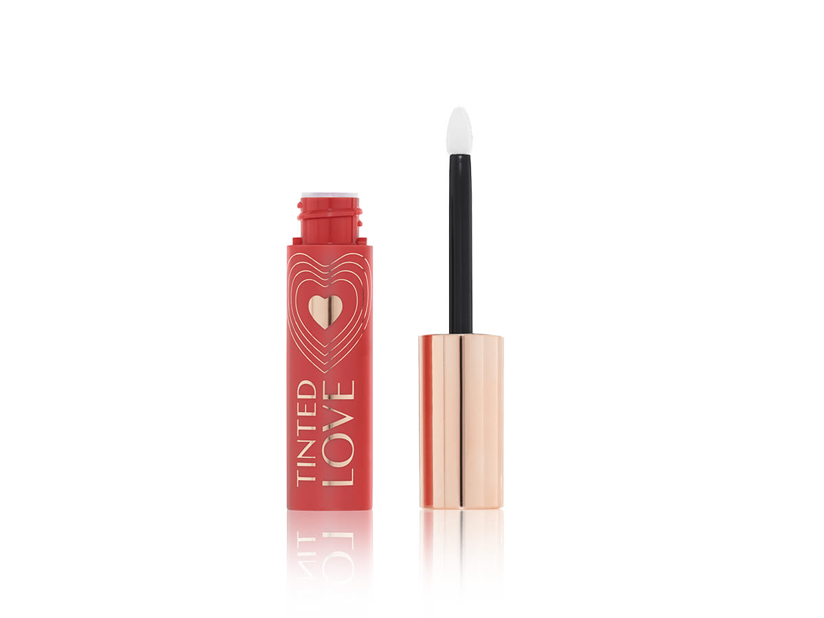 Tinted Love in Bohemian Kiss open An open lip and cheek tint in a warm peachy-brown shade with a matching-coloured bottle with a white and gold-coloured doe-foot applicator.