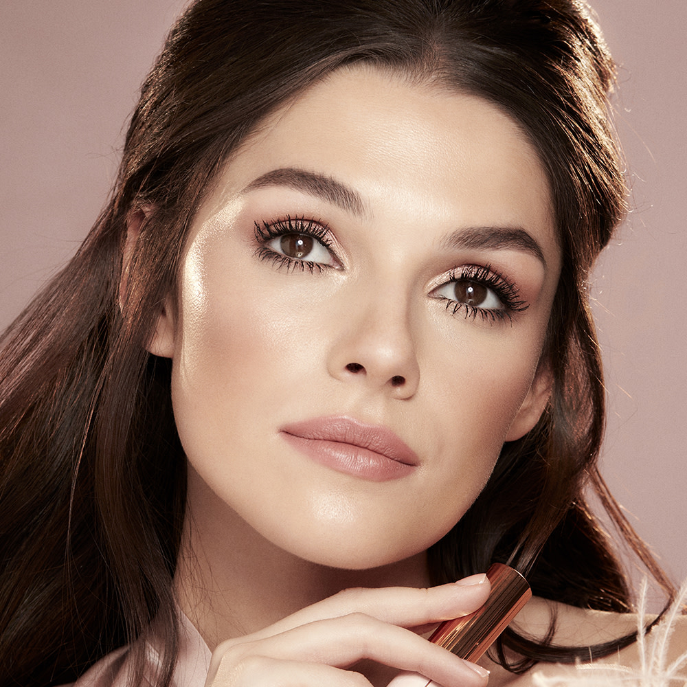 Fair skin model with brown eyes wearing nude pink lipstick with muted pink blush, and lengthening mascara in a black shade. 