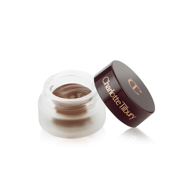 An open frosted glass pot with a cream eyeshadow in a chocolate brown shade with a matte finish with a dark brown lid with Charlotte Tilbury written on the lid in gold. 