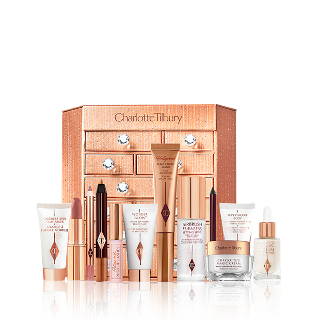 Charlotte's Bejewelled Chest of Beauty Treasures closed with products A golden-coloured chest of drawers with a clay mask, nude pink matte lipstick, nude pink lip liner, eyeliner pencil in dark copper, black-coloured mascara, liquid primer, champagne-coloured liquid highlighter, dark brown eyeliner pencil, pearly-white face cream, luminous ivory-coloured serum, and bronze-coloured body highlighter.