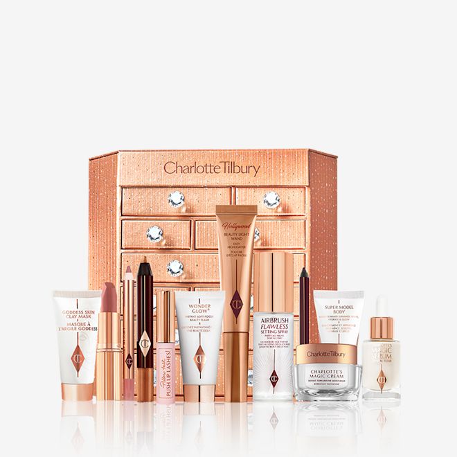 Charlotte's Bejewelled Chest of Beauty Treasures closed with products A golden-coloured chest of drawers with a clay mask, nude pink matte lipstick, nude pink lip liner, eyeliner pencil in dark copper, black-coloured mascara, liquid primer, champagne-coloured liquid highlighter, dark brown eyeliner pencil, pearly-white face cream, luminous ivory-coloured serum, and bronze-coloured body highlighter.