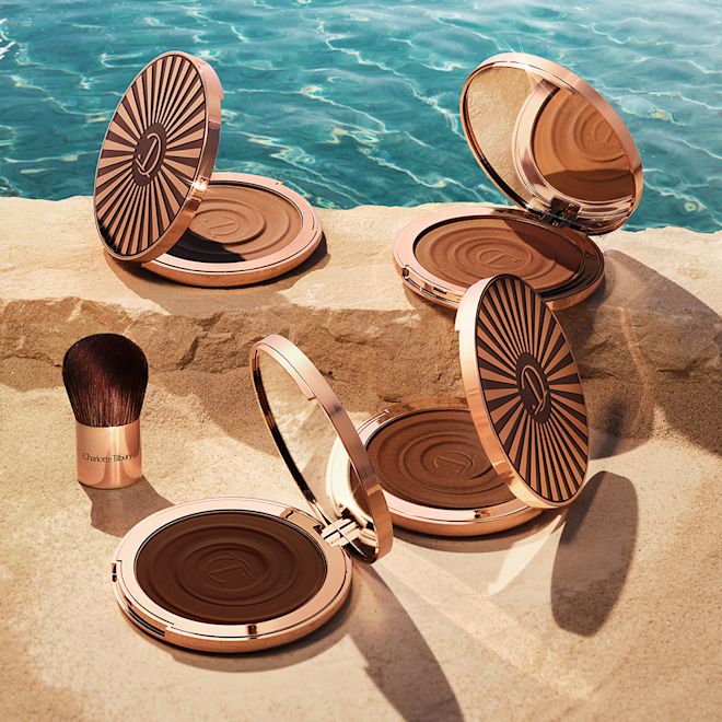 Beautiful Skin Sun-Kissed Glow Bronzer collection open Four, open cream bronzer compacts with mirrored lids in light brown, medium brown, dark brown, and black-brown shades with gold-coloured bodies and lids.