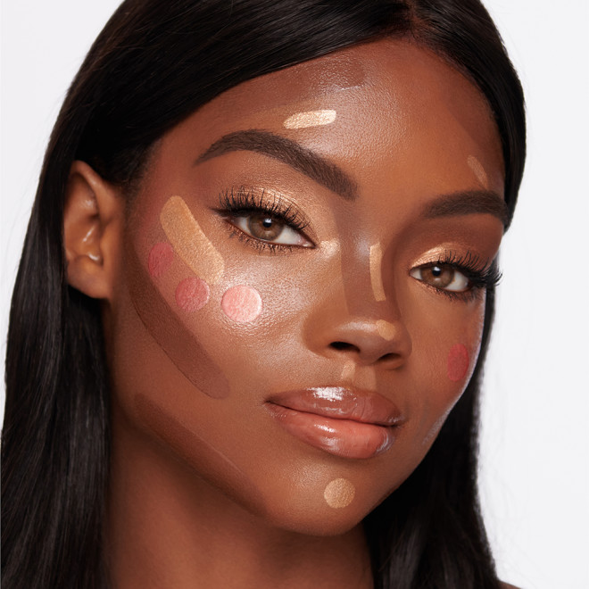 Deep-tone brunette model with contour, soft golden liquid highlighter, and glowy liquid blush in medium-pink applied on her face but not blended yet.