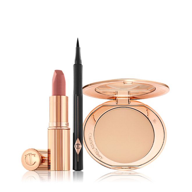 Airbrush Complexion Feline Flick Pillow Talk Kit An open nude-pink lipstick in a golden tube with an open black eyeliner pen, and open, mirrored-lid pressed compact in a light shade.