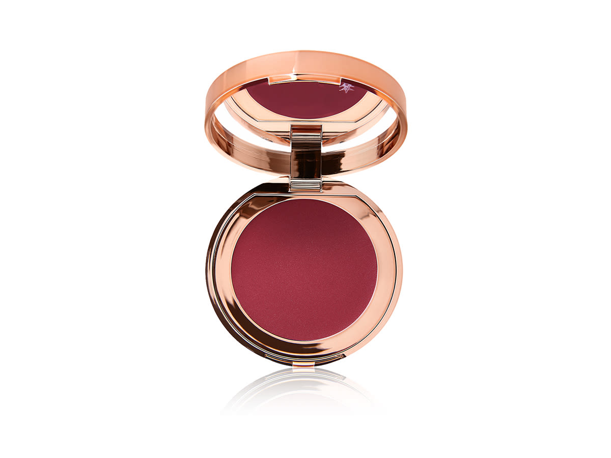 Pillow Talk Lip and Cheek Glow in Colour of Passion open An open, mirrored-lid lip and cheek cream compact in a berry-red shade.