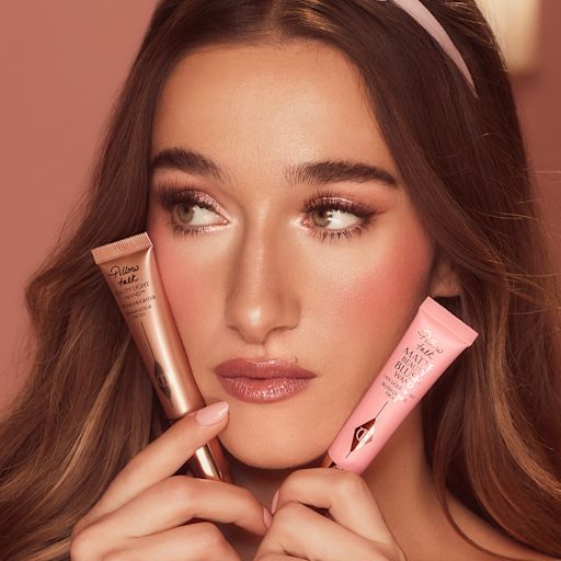 Bella holding and wearing Beauty Blush Wands and Beauty Light Wands A fair skin model holding and wearing a liquid blush and liquid highligher