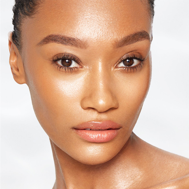 A deep-tone brunette model with freshly-cleansed and moisturised glowing and flawless, glass skin. 