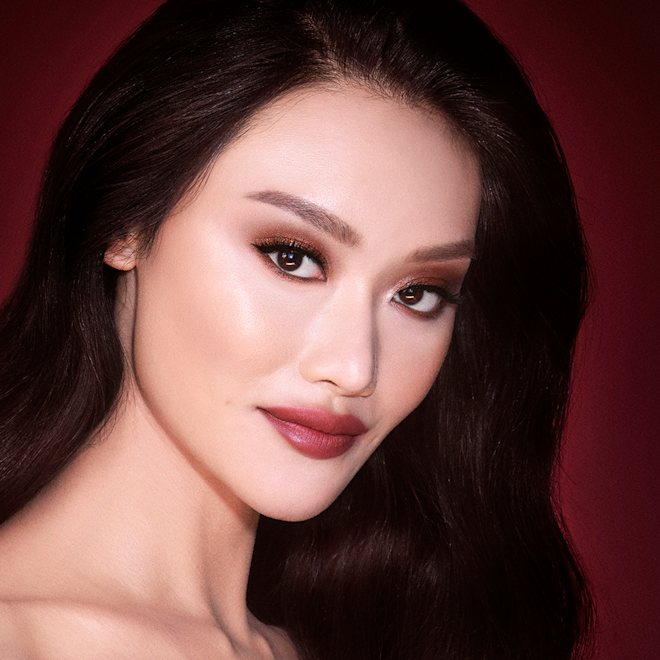 The Bella Sofia Look on fair tone brunette model A fair-tone model with brown eyes with shimmery copper, gold, and brown eye makeup with black eyeliner and matte, berry-pink lips.