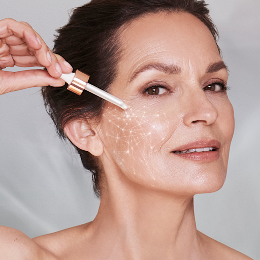 Magic Serum Crystal Elixir on mature-skin model A fair-tone model with mature skin applying a pearlescent serum on her face.