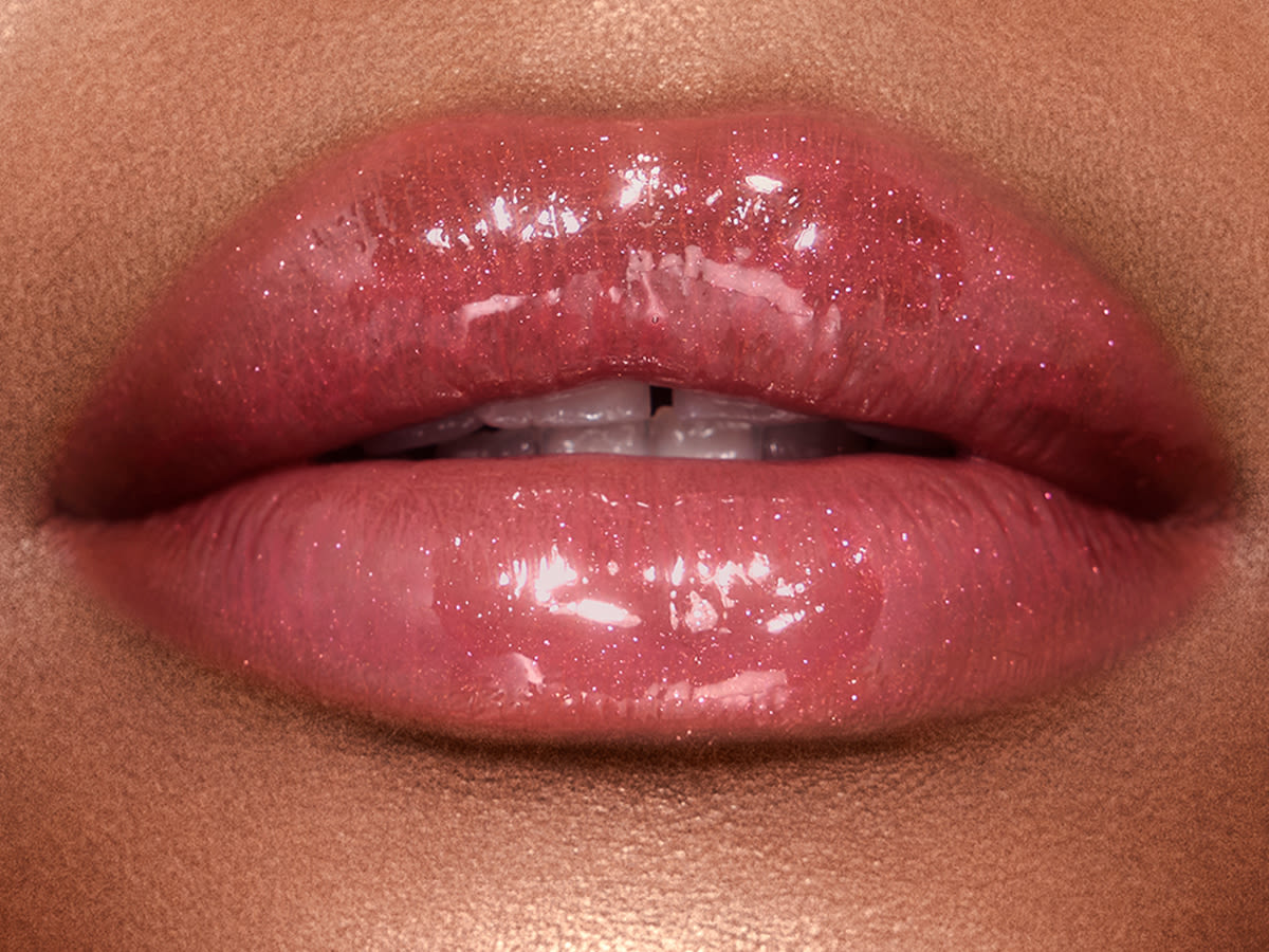 Jewel Pots in Walk of No Shame on deep-tone model lips close-up Lips close-up of a deep-tone model wearing shimmery berry-pink lip gloss.