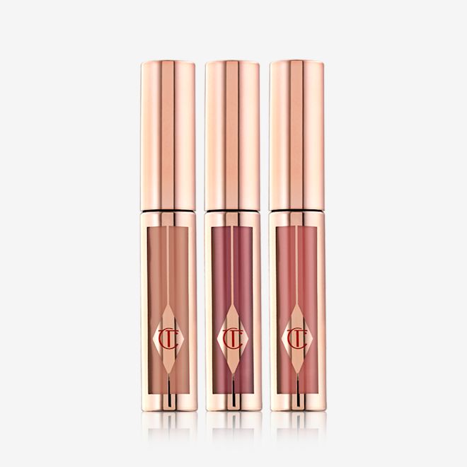 Hollywood Lips Trio closed A trio of liquid lipsticks in clear tubes with gold-coloured lids in shades of light brown, muted purple wine, and nude pink.