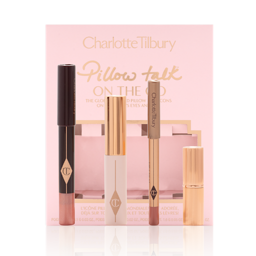 Pillow Talk On The Go with box displayed An unpacked makeup kit that includes an eyeshadow pencil in a rose gold shade, mascara, lip liner pencil in nude pink, and lipstick in a nude pink shade with the packaging box in a nude pink colour behind the products.