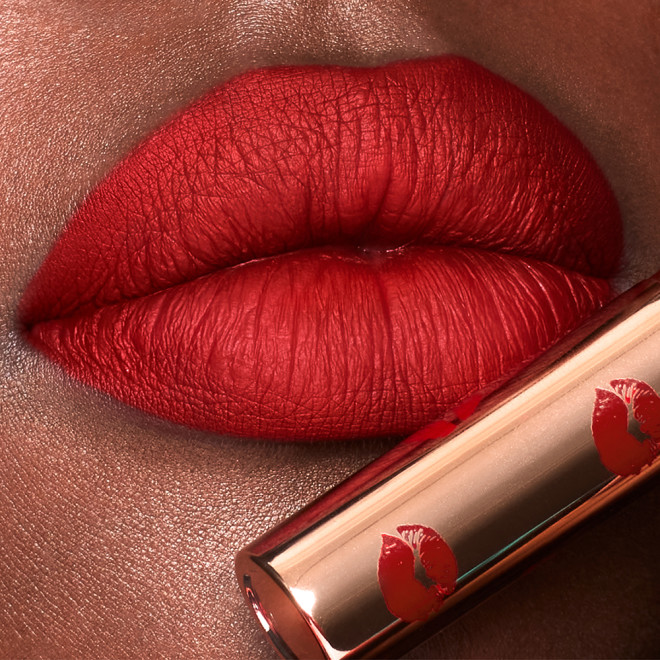 Lips close-up of a deep-tone model wearing poppy red lipstick with a matte finish.
