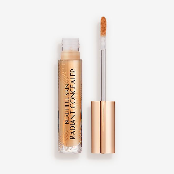 Beautiful Skin Radiant in Concealer in 7.5 lid removed Radiant concealer in a glass tube with its doe-foot applicator next to it with a gold-coloured handle.