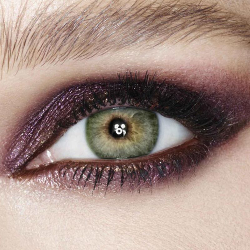 Eye close-up of a light tone model with green eyes wearing smokey purple eyeshadow. 