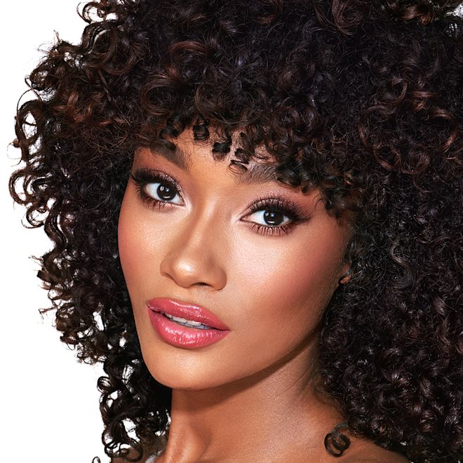 The Supermodel look on deep-tone model A deep-tone model with brown eyes wearing soft fawn and brown eye makeup with glowy terracotta blush, and sheer, glossy rose-pink lips.