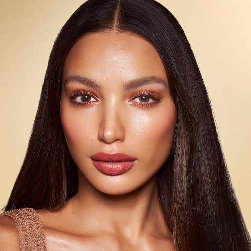 Medium-tone brunette model wearing lip and cheek colour stick in a glowy soft pink shade with eyeshadow in a sultry- sunset-pink shimmer shade.
