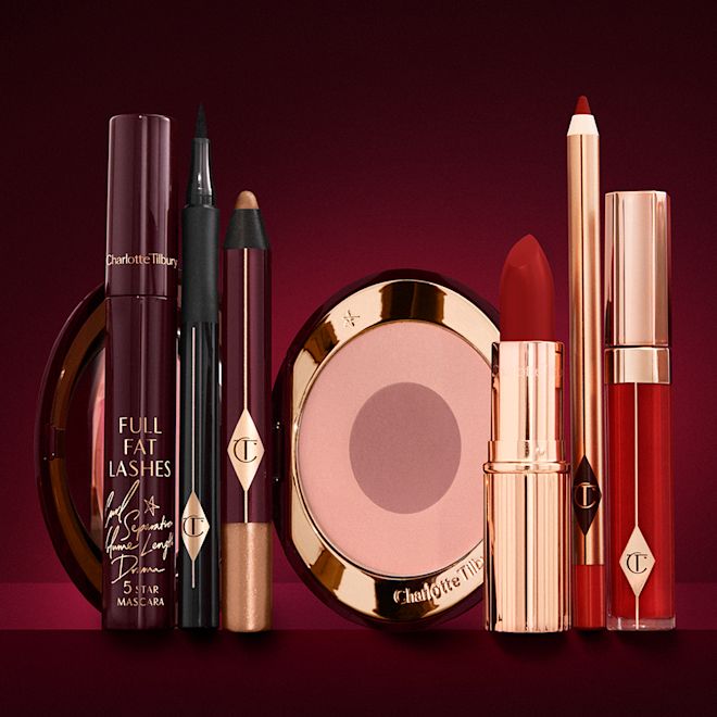 The Bombshell kit for fair to medium displayed An open two-tone blush in cool-toned pink and brown with a mascara, eyeliner pen, chubby eyeshadow stick in gold, an open lipstick in bold red, lip liner pencil in blood-red, and a lip gloss in bright red.