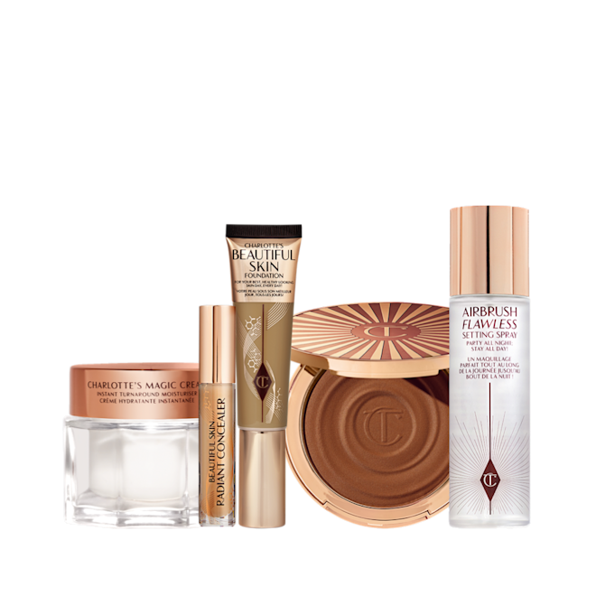 5 Steps To Beautiful Skin kit displayed Foundation in a sleek gold-coloured tube with a concealer in a glass tube and gold-coloured lid, dark brown cream bronzer compact in gold-coloured packaging, setting spray in a large, clear bottle with a gold-coloured lid, and pearly-white face cream in a glass jar with a gold-coloured lid.