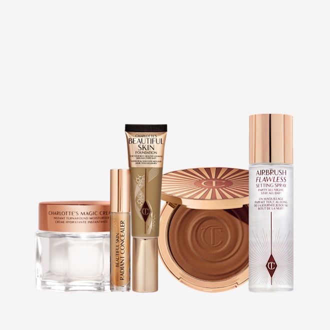 5 Steps To Beautiful Skin kit displayed Foundation in a sleek gold-coloured tube with a concealer in a glass tube and gold-coloured lid, dark brown cream bronzer compact in gold-coloured packaging, setting spray in a large, clear bottle with a gold-coloured lid, and pearly-white face cream in a glass jar with a gold-coloured lid.
