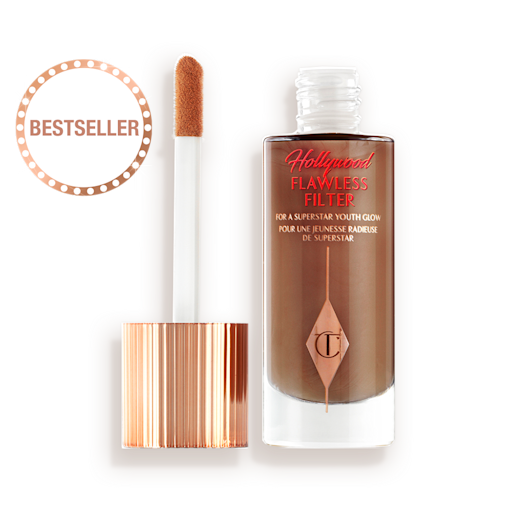 HFF-8-LEGENDARY-PDP 1 An open, luminous primer in a dark brown shade in a glass bottle with its gold and white doe-foot applicator next to it.