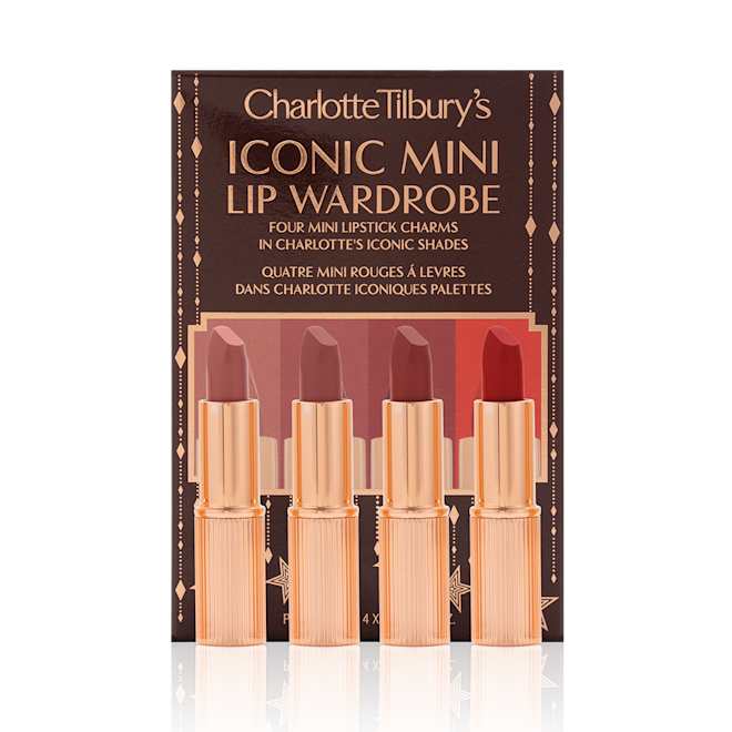 Iconic Mini Lip Wardrobe with box displayed Five matte lipsticks in nude shades of red and pink in sleek, gold-coloured tubes with their dark-brown gift set box behind them with text written on the front that reads, 'Charlotte Tilbury's Iconic mini lip wardrobe'.