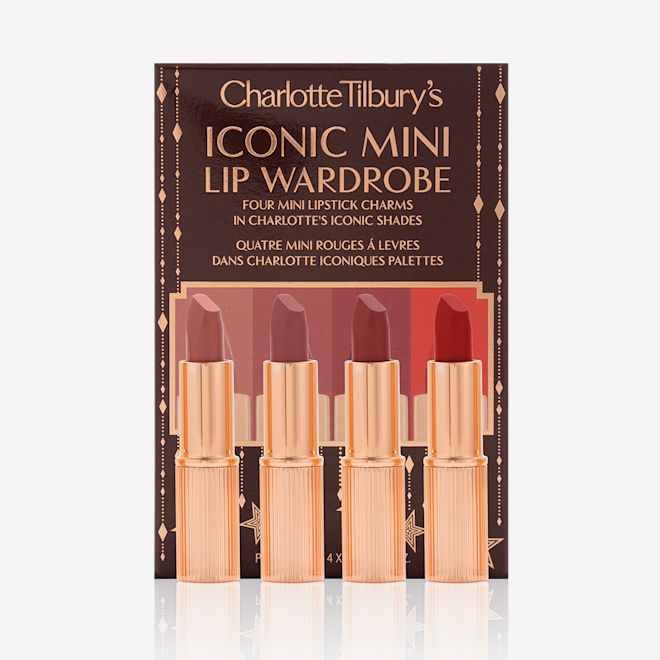Iconic Mini Lip Wardrobe with box displayed Five matte lipsticks in nude shades of red and pink in sleek, gold-coloured tubes with their dark-brown gift set box behind them with text written on the front that reads, 'Charlotte Tilbury's Iconic mini lip wardrobe'.