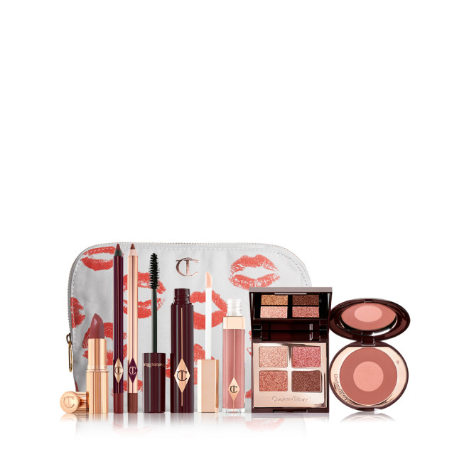 A white makeup pouch with open products displayed, which include a berry-rose lipstick, maroon eyeliner pen, berry-rose lip liner pencil, mascara, nude-pink lip gloss, a mirrored-lid quad eyeshadow palette, and a two-tone warm-pink blush. 