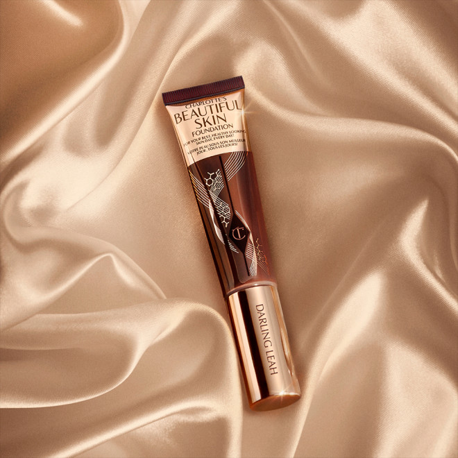 A foundation wand in gold, engraved packaging with a dark-brown-coloured body to show the shade of the foundation inside. 