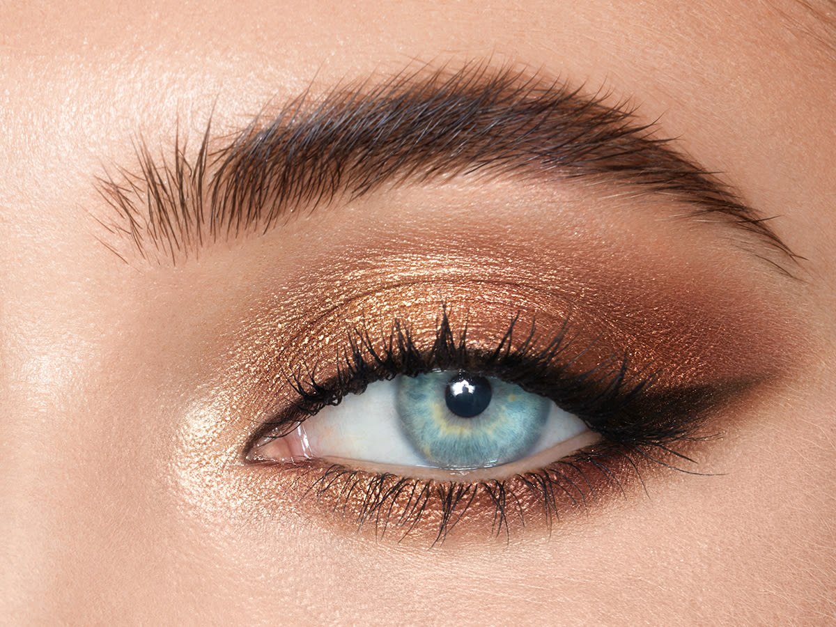 The Icons Eyeshadow Palette gold look on blue eyes close-up Close-up of a light-tone model's blue eye with shimmery gold, bronze, and champagne eye makeup.
