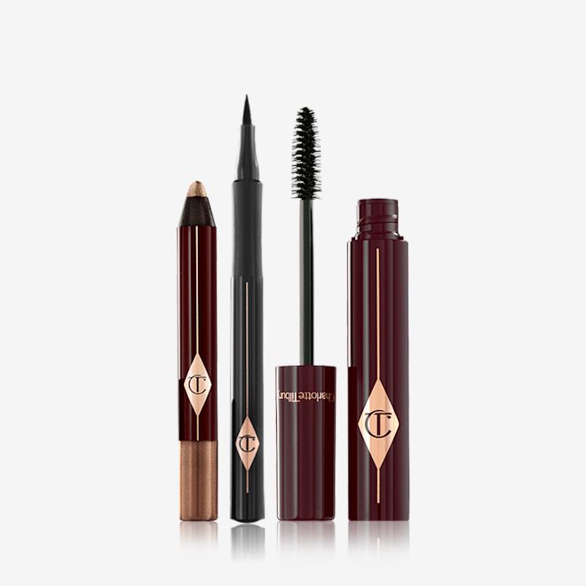 The Bombshell Eye Kit open An open chubby eyeshadow stick in bronze, an open eyeliner pen in black, and an open mascara tube with its applicator next to it.