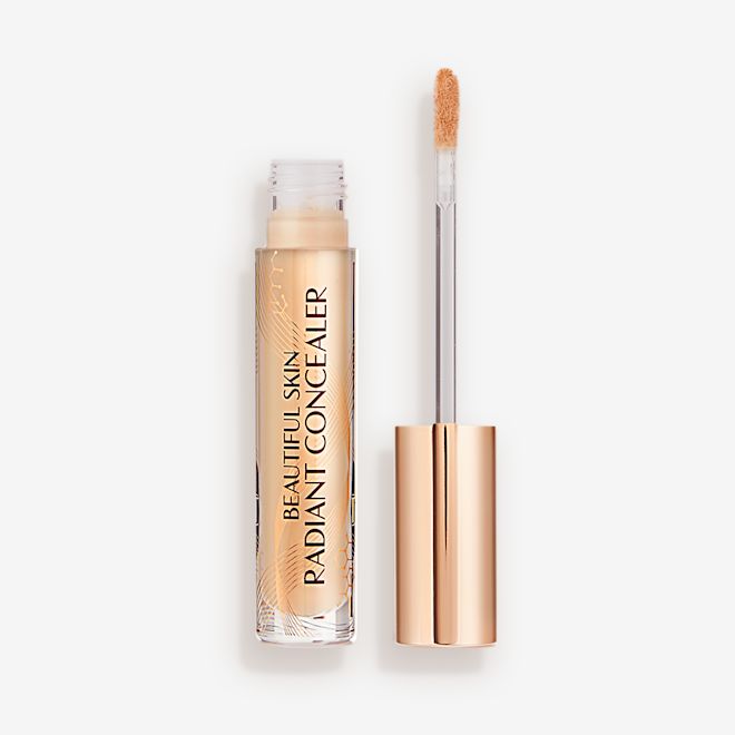 Beautiful Skin Radiant in Concealer in 6.5 lid removed Radiant concealer in a glass tube with its doe-foot applicator next to it with a gold-coloured handle.