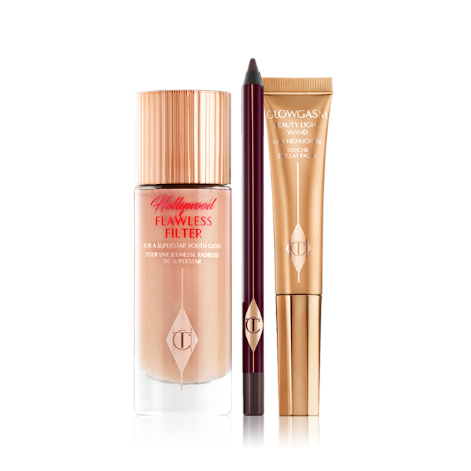 Smokey Eye Glowing Skin Makeup Kit A luminous, champagne-coloured creamy primer in a glass bottle, an open kohl liner pencil in dark brown, and a highlighter wand in a warm golden-coloured packaging.