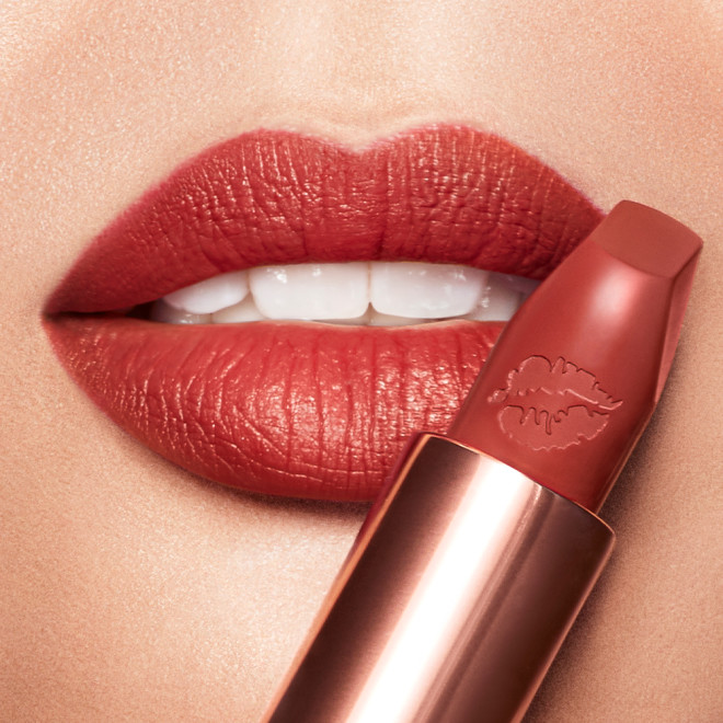 Light-tone model wearing a muted, matte brick red lipstick. 