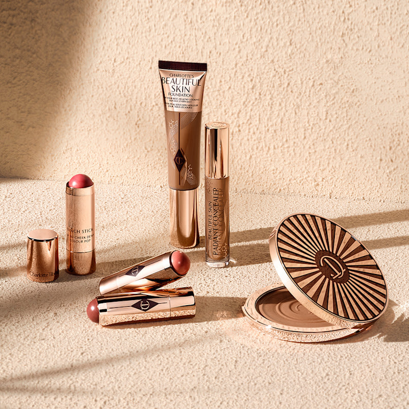 Cream products still life Charlotte's Beautiful Skin collection and Beach Sticks cream blush sticks on a beachy backdrop