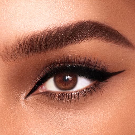 The Feline Flick Eyeliner in Panther brown eye close-up Eye close-up of a medium-tone model with brown eyes wearing a jet black eyeliner in a sharp, cat-eye winged shape.