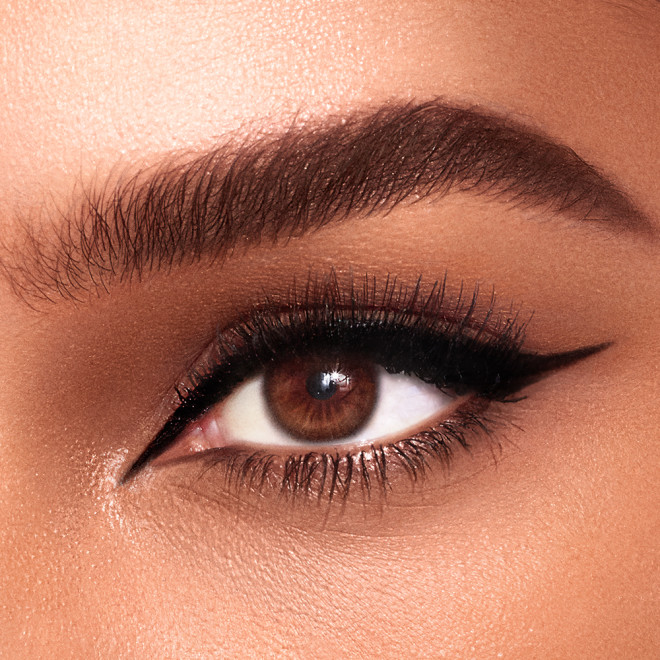 Eye close-up of a medium-tone model with brown eyes wearing a jet black eyeliner in a sharp, cat-eye winged shape.