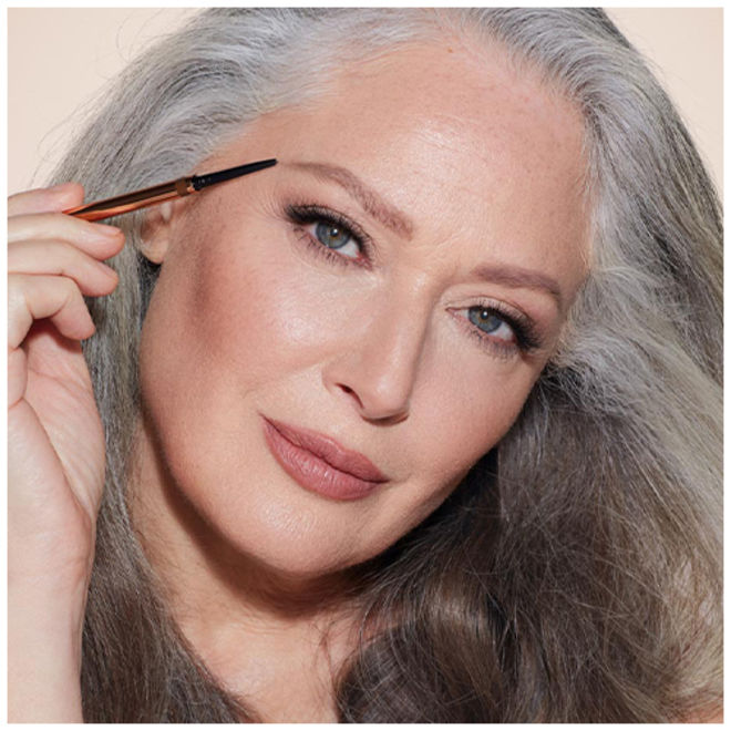 Brow Cheat in Taupe on fair-tone model with grey eyes Fair-tone model with grey eyes applying a taupe-coloured eyebrow pencil.