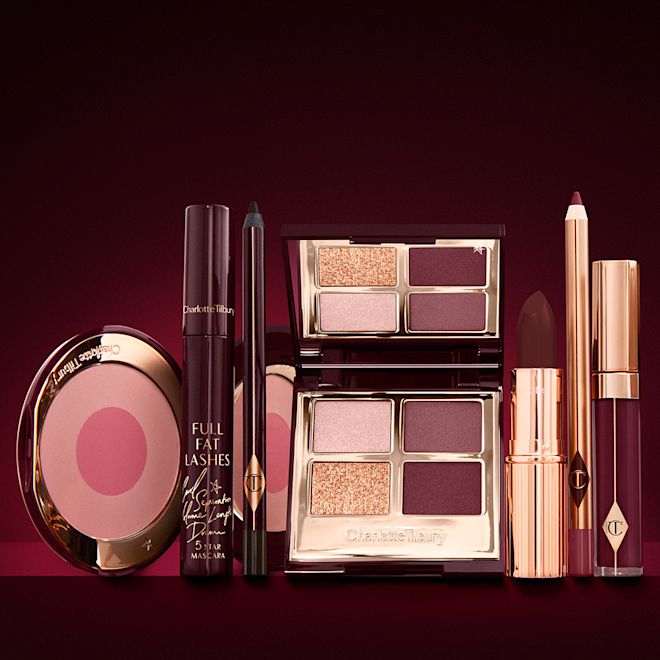 The Vintage Vamp Deep Look kit displayed An open two-tone blush in fuchsia and warm pink with a mascara, eyeliner pencil, quad eyeshadow palette with shimmery and matte brown and golden shades, an open lipstick in crimson red, lip liner pencil in wine, and a lip gloss in vampy red.